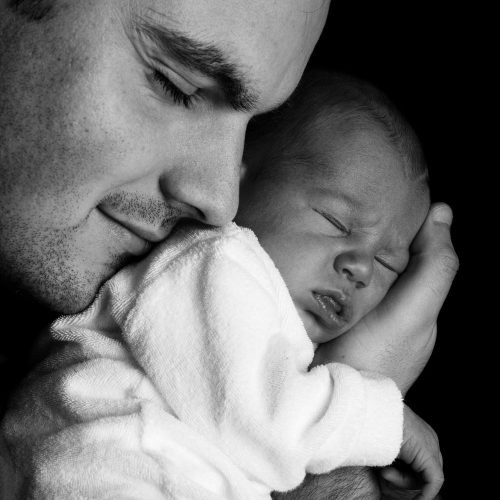 Sleeping baby held by father in black and white – Birth, Baby & You – Dee Bell – Lactation Consultant for Kent, Surrey & Sussex